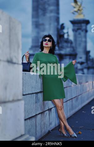 Das glamouröse Paris, Faubourg Saint-Germain in der Abenddämmerung, eine modische Asiatin am Quai d'Orsay von Pont Alexandre III. In einem eleganten, smaragdgrünen Kleid Stockfoto