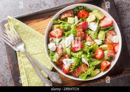 Erdbeer-Avocado-Salat mit Feta, Speck und Salat in einer Schüssel auf dem Tisch. Horizontale Draufsicht von oben Stockfoto