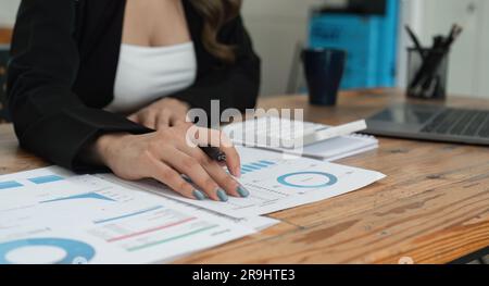 Nahaufnahme der Hände einer Geschäftsfrau mit einem Taschenrechner, um die Finanzen und Einnahmen des Unternehmens sowie das Budget zu prüfen. Geschäftsfrau, die die monatlichen Ausgaben berechnet Stockfoto