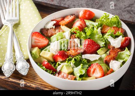 Erdbeer-Avocado-Salat mit Feta, Speck und Salat in einer Schüssel auf dem Tisch. Horizontal Stockfoto