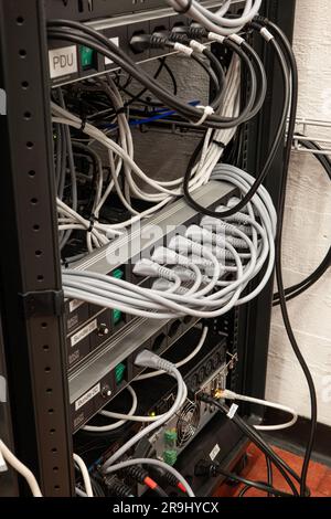 Übersichtlich organisierte Verlängerungskabel für Netzkabel mit vollständig verwendeten Steckern auf einem Industrie-Rack. Drinnen, keine Leute. Stockfoto