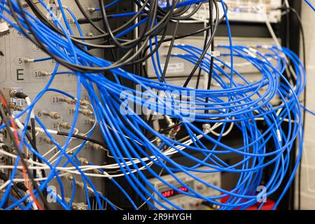 Unordentliche blaue elektrische Kabel, die mit industriellen Laborgeräten verbunden sind, keine Menschen. Stockfoto