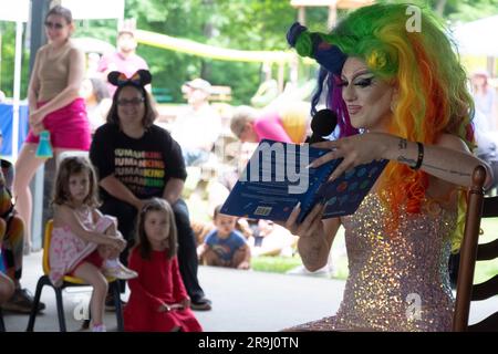 Ein Drag Performer liest ein Buch zu Kindern mit dem Namen Einpassen, über Inklusivität. In Lewisboro, Westchester, bei einer Pride-Veranstaltung. Juni 2023. Stockfoto