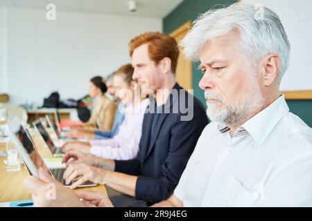 Geschäftsmann, der von Kollegen am Arbeitsplatz einen Tablet-PC verwendet Stockfoto