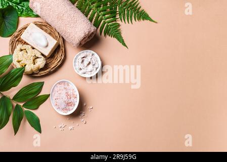 Spa-Hintergrund. Natürliche organische Spa-Kosmetikprodukte mit grünen Blättern, umweltfreundliche Badaccessoires. Körperpflege-Massagekonzept auf beigem Hintergrund, Stockfoto