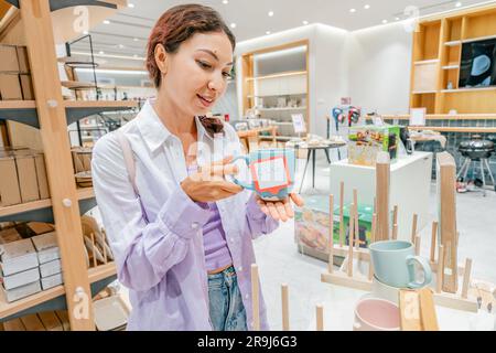 Eine Hausfrau sucht sich im Laden Tassen und Haushaltsgeräte aus Stockfoto