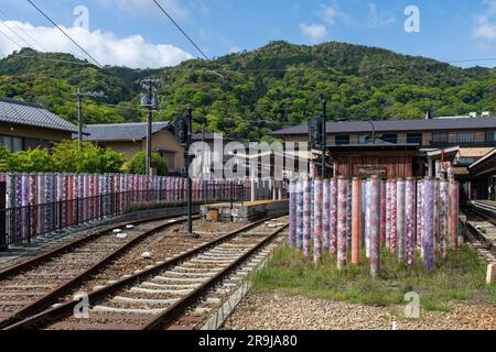 Arashiyama, Japan - April 2023; Blick über die Gleise in der Nähe des Bahnhofs Arashiyama Randen neben den zylindrischen Acrylfasersäulen des Kimono-Waldes mit Textil Stockfoto