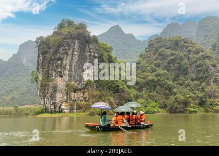 Ninh Binh, Vietnam-April 2023; Blick auf Ruderboote im Sampan mit Touristen auf Höhlentouren auf dem Red River Delta in der Landschaft von Trang und zwischen bewaldeten li Stockfoto