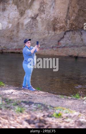 Eine Frau, die mit ihrem Smartphone ein Foto vom wunderschönen Fluss macht. Stockfoto