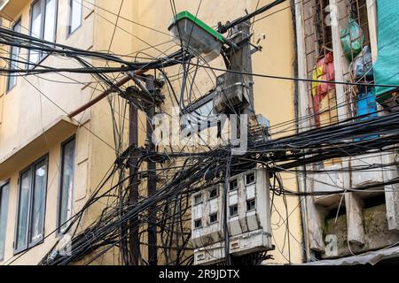 Blick auf die Fassade typischer Häuser in Hanoi, Vietnam, mit Stromkabeln, Telefonleitungen, die durcheinander und chaotisch gegeneinander hängen Stockfoto