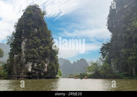 Panoramablick auf das Red River Delta von Ninh bin, Vietnam mit Ruderbooten im Sampan mit Touristen auf Höhlentouren, umgeben von bewaldeten Kalksteinfelsen Stockfoto