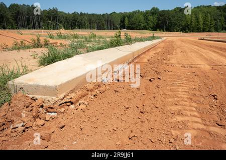 Betonkanten in neuen Wohngebieten wurden auf roten Lehmboden gegossen. Stockfoto