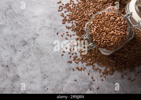 Leinsamen in einem Glasgefäß auf einem grauen, strukturierten Hintergrund, Draufsicht. Gesundes Essen, Superfood. Stockfoto