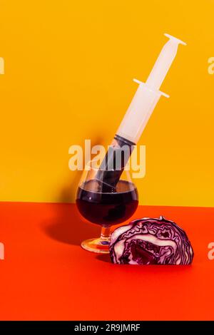 Antioxidans-gesunder Saft aus Rotkohl-Gemüse, extrahiert in Glas mit Spritze auf hellem Hintergrund mit Kohl Stockfoto