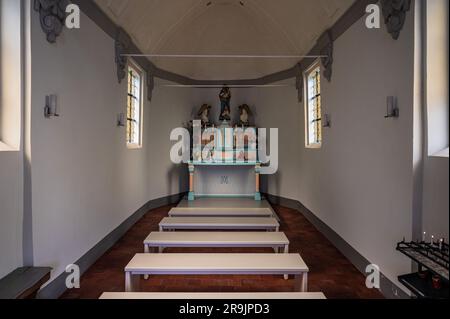 Laarne, Ostflämische Region, Belgien, 16. Juni 2023 - Innendesign der Berlinde-Kapelle mit weißen Bänken und einem Altar Stockfoto