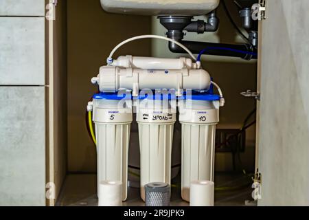 Fotografie zum Thema Wasserfiltersystem für zu Hause in der Küche im Hintergrund, Foto bestehend aus der Installation eines Wasserfiltersystems für zu Hause, Ersatzwasser Stockfoto