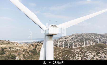 Eine malerische Landschaft mit mehreren Flügeln von Windturbinen, die sich seitlich am Hügel befinden, mit einem klaren blauen Himmel im Hintergrund Stockfoto