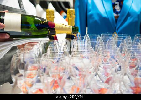Der Kellner schüttet Weißwein in Gläser bei einer Party. Stockfoto