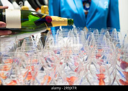 Der Kellner schüttet Weißwein in Gläser bei einer Party. Stockfoto