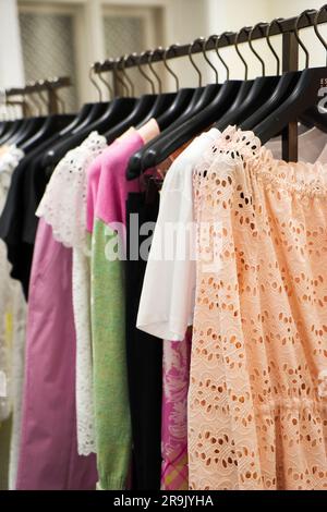 Bunte Damenkleider auf Kleiderbügeln in einem Modegeschäft. Hol dir stylische Kleidung und Nahaufnahmen. - Bild Stockfoto