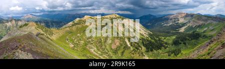 Peeler Peak - Ein Panoramablick auf den Peeler Peak der Elk Mountains im Sommer mit dunklen Sturmwolken über dem Mount Crested Butte im Hintergrund. CO, USA. Stockfoto