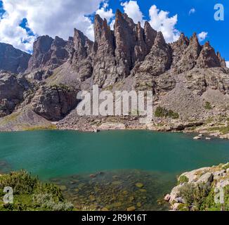 Sky Pond und Sharkstooth - Ein sonniger Sommertag mit Blick auf den klaren und farbenfrohen Sky Pond, mit zerklüfteten Haifischspitzen, die an der Küste hoch aufragen. RMNP, CO. Stockfoto