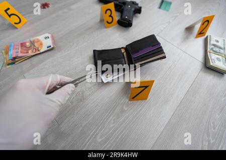 Extreme Nahaufnahme mit verschwommenem Hintergrund: Hand mit medizinischem Handschuh mit Pinzette zum Halten einer Kugelschale. Forensik Specialist findet Kassette auf Stockfoto
