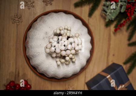 Weihnachtlicher Cupcake, Geschenke und Kiefernäste auf Holzhintergrund, Draufsicht. Christmass Symbole Süßigkeiten, Kerzen, Zimt, Schneeflocken. Christmass Stockfoto