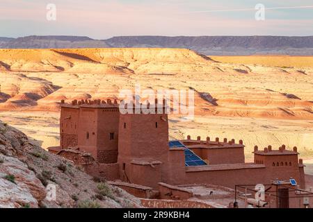 Alte Burg auf einem Hügel über der Wüstenlandschaft bei Sonnenuntergang, Ait Ben Haddou, Provinz Ouarzazate, Marokko Stockfoto