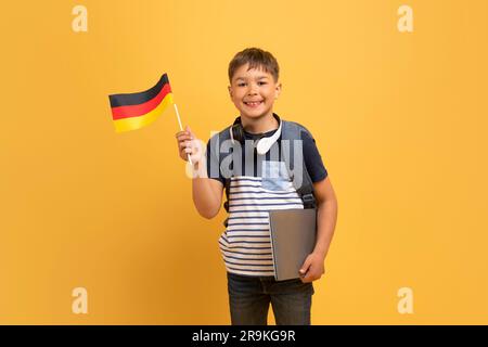 Fröhlicher Schuljunge mit deutscher Flagge und gelbem Hintergrund Stockfoto