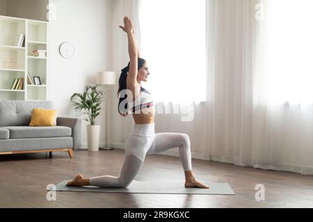 Wunderschöne, sportliche junge Frau, die zu Hause Yoga praktiziert Stockfoto