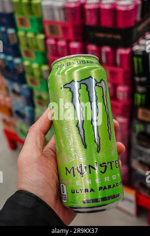 Eine Hand, die eine Dose Monster Energy Drink im Supermarkt hält Stockfoto