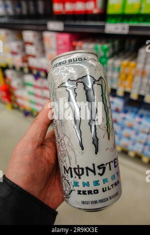 Eine Hand, die eine Dose Monster Energy Drink im Supermarkt hält Stockfoto