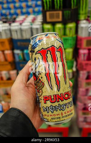 Eine Hand, die eine Dose Monster Energy Drink im Supermarkt hält Stockfoto