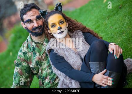 Ein junges Paar trägt Wolfs- und Holzfäller-Kostüme. Eine echte Familie, die Spaß hat, während sie Kostüme der kleinen roten Reithaubengeschichte an Halloween verwendet. Stockfoto