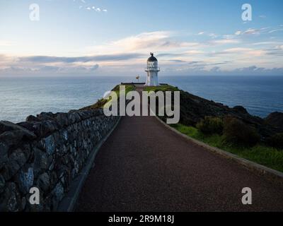 Fußgängerweg auf Asphaltstraße, der zum historischen weißen Leuchtturm führt, hoch oben auf den Klippen am Meer Cape Reinga Aupouri Halbinsel Northland Nr. Stockfoto