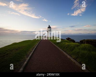 Fußgängerweg auf Asphaltstraße, der zum historischen weißen Leuchtturm führt, hoch oben auf den Klippen am Meer Cape Reinga Aupouri Halbinsel Northland Nr. Stockfoto