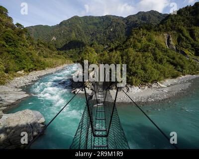 Die Hängebrücke aus Metall in der Caesspool Gorge führt über den türkisfarbenen, kristallklaren, blauen Wasserfluss am Arahura River an der Westküste der Südinsel Neuseeland Stockfoto