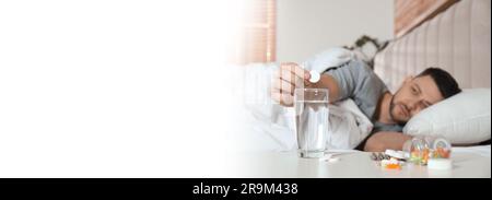 Mann nimmt Medizin gegen Kater im Bett zu Hause, selektive Fokussierung. Bannerdesign mit Platz für Text Stockfoto