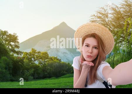 Schöne Frau mit Strohhut, die Selfie in den Bergen macht Stockfoto