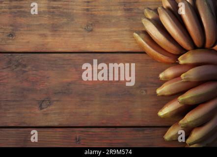 Leckere lila Bananen auf einem Holztisch, Blick von oben. Platz für Text Stockfoto