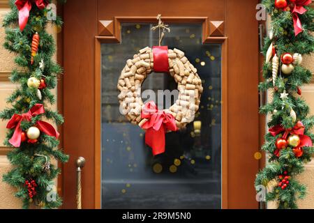 Wunderschöner Weihnachtskranz aus Weinkorken, die an einer Holztür hängen Stockfoto