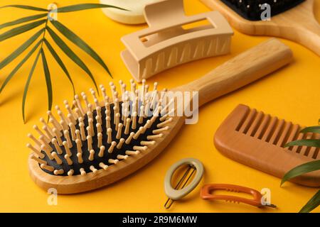Holzbürsten, Kamm und verschiedene Haarprodukte auf orangefarbenem Hintergrund Stockfoto
