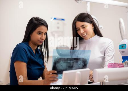 Junge Ärztin, die mit ihrem Patienten Röntgenuntersuchungen in einer Arztpraxis, Berufsausübung und Krankheitsprävention überprüft Stockfoto