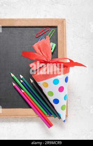 Rote Schulkegel mit verschiedenen Schreibwaren und Tafel auf weißem Hintergrund Stockfoto