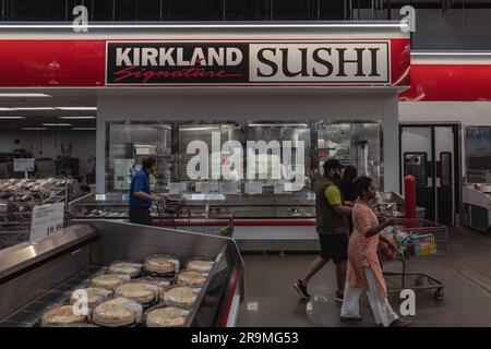 Ein lebendiges Bild zeigt eine lebendige Szene in einem Costco Food Court. Die Gäste werden geduldig warten sehen, und freuen sich darauf, das neu eingeführte Sushi zu probieren. Die Aufregung in der Luft ist spürbar, wenn sich Menschen an der Essenstheke versammeln. Costco, der renommierte Großhändler, hat einen mutigen Schritt getan und sein preisgünstiges Speisenangebot um Sushi ergänzt. Die Einführung dieser neuen Küche hat zu langen Warteschlangen und längeren Wartezeiten geführt, da eifrige Mitglieder sich beeilen, das neueste Angebot von Costco zu probieren.Kunden verschwenden keine Zeit, um ihre Meinung online zu teilen, was zu einem Aufschwung führt Stockfoto