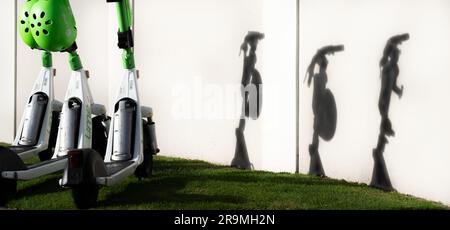 Tauranga Neuseeland - 26 2023. Juni; Schatten von drei geparkten Lime-Elektrorollern an der Wand Stockfoto