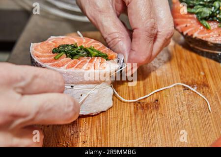 Der Küchenchef bereitet Lachs mit Spinat und gebackener Zitrone und Sauce zu. Französische Gourmetküche. Stockfoto