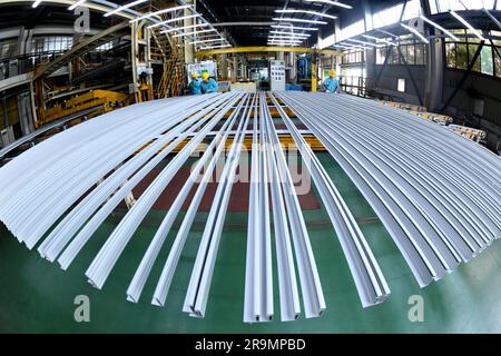 HAI'AN, CHINA - 28. JUNI 2023 - Arbeiter verarbeiten Aluminiumrahmen für Photovoltaik-Kraftwerke in einer Werkstatt in Hai'an, Provinz Jiangsu, China, Stockfoto