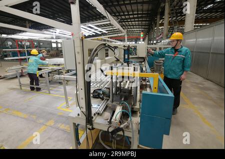 HAI'AN, CHINA - 28. JUNI 2023 - Arbeiter verarbeiten Aluminiumrahmen für Photovoltaik-Kraftwerke in einer Werkstatt in Hai'an, Provinz Jiangsu, China, Stockfoto